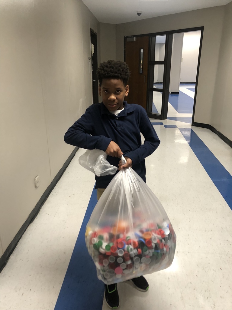 A student holds a bag of bottle caps.