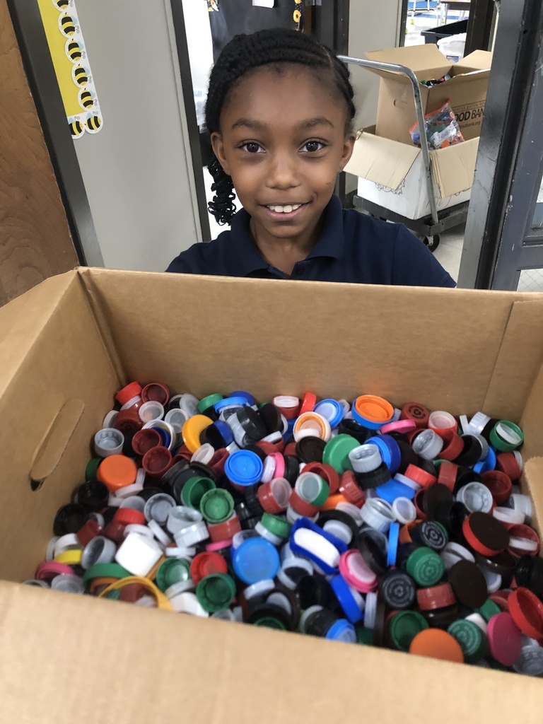 A student holds a box of bottle caps.
