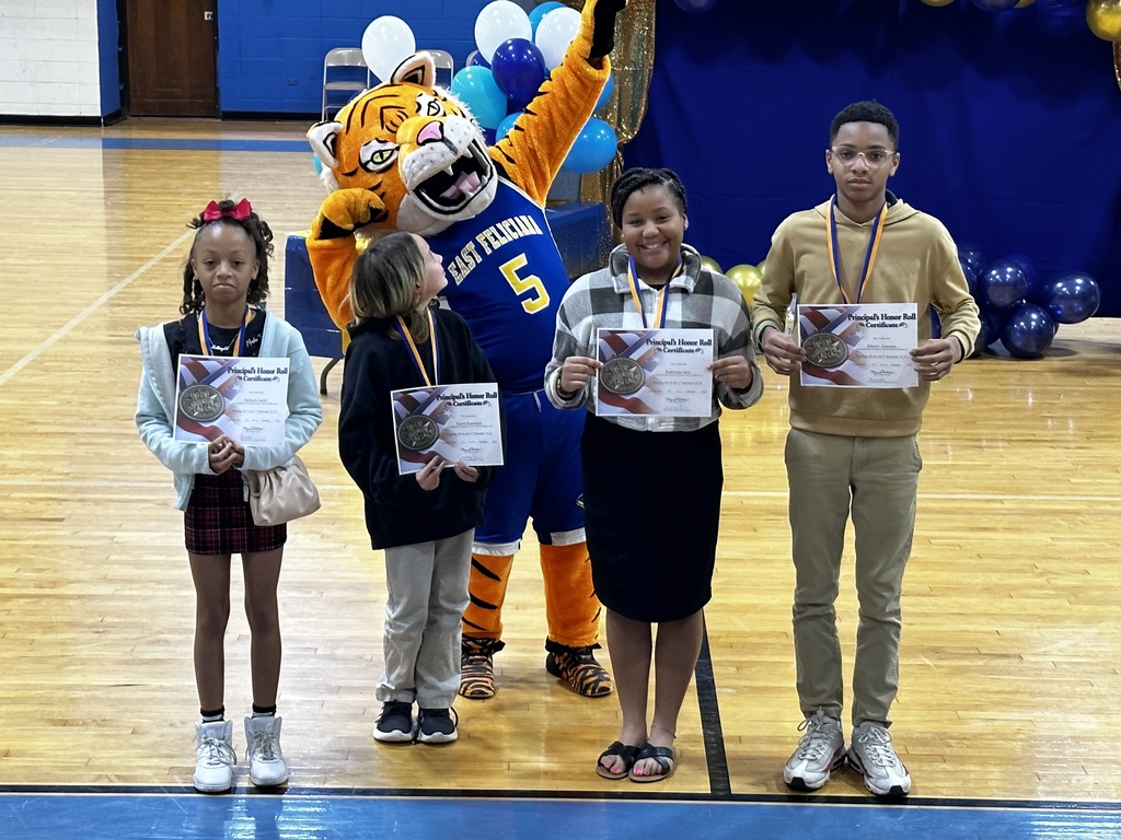 Four older students stand in front of a Tiger mascot.