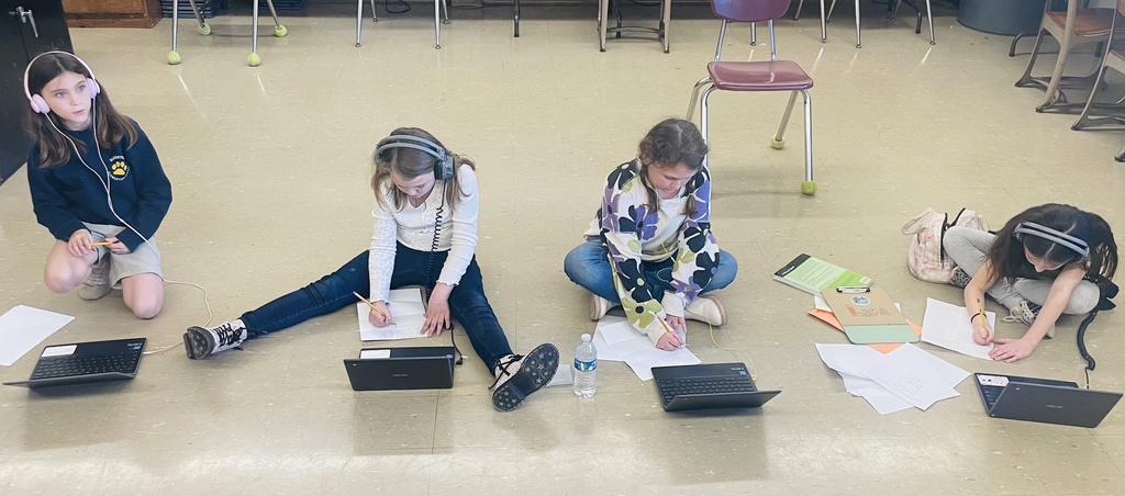A group of students with pencil and paper are sitting in front of Chromebooks comfortably.