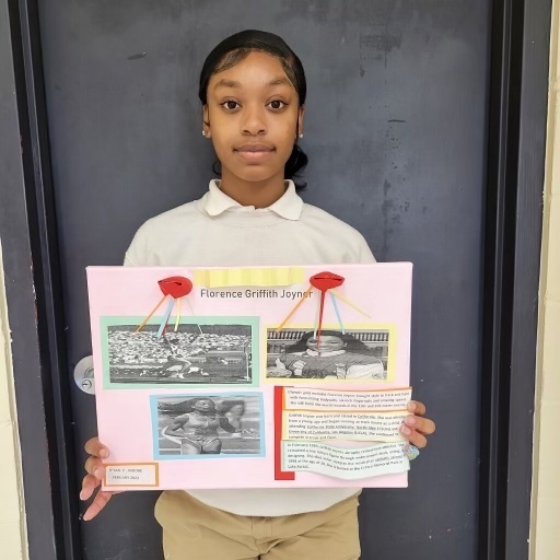 A student holds up a poster with text and pictures.