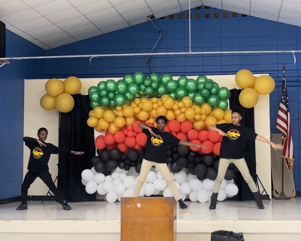 Three students perform a step routine in front of a balloon display.