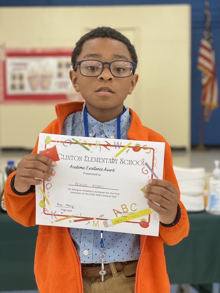 A child in glasses holds up a certificate.