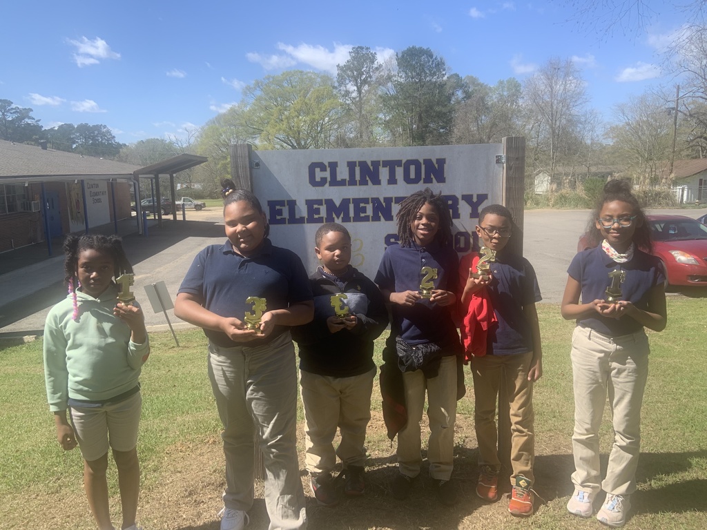 Six students stand with trophies in front of the Clinton Elementary School sign.