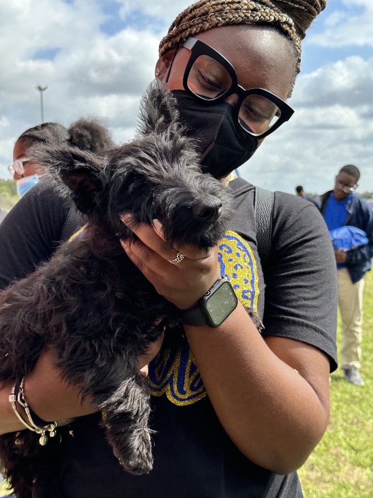 A person in glasses holds a dog.