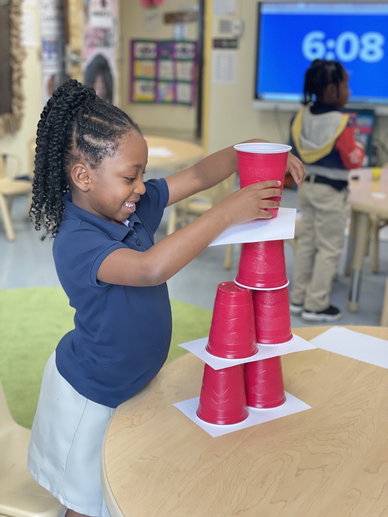 A child is smiling as she stacks red cups.
