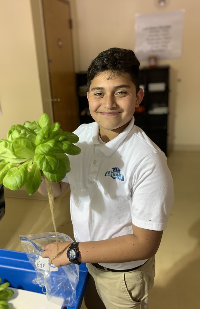 A student holds up a bundle of lettuce.