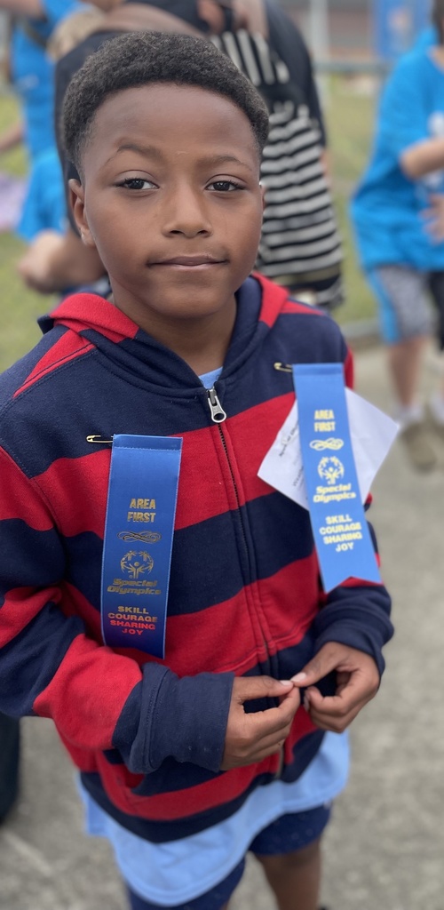 A child wearing two blue ribbons has a gentle smile.