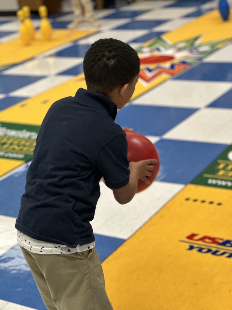 A child focusing on a bowling lane holds a bowling ball.