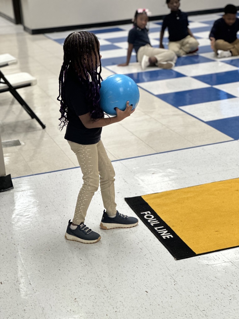 A child holding a blue bowling ball approaches the bowling lane.