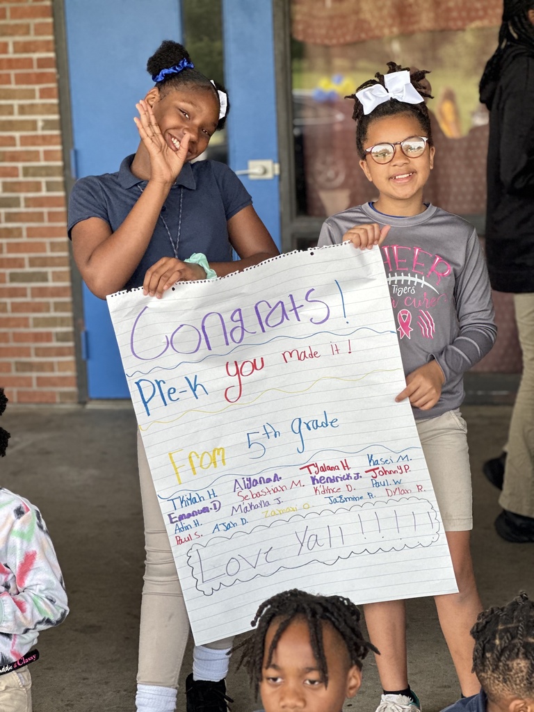 Smiling children hold a poster with encouraging remarks.