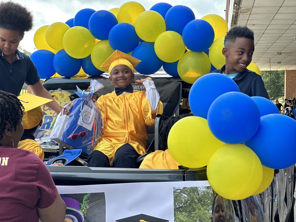 A pre-k student in a gold robe in a truck bed with balloons.
