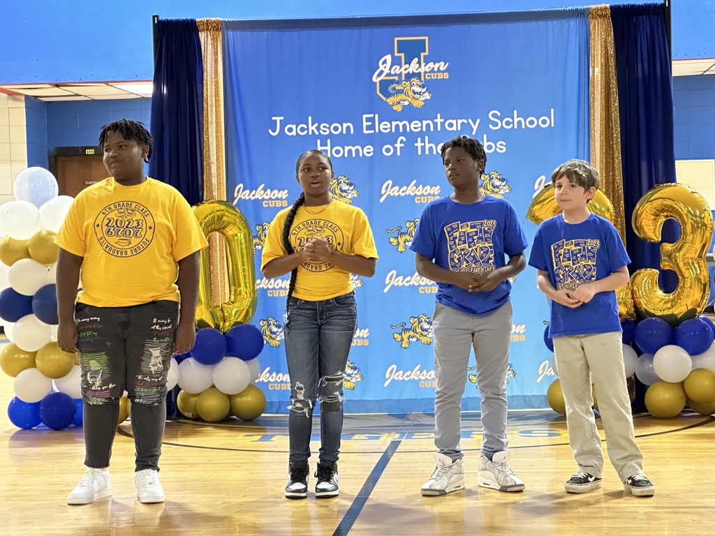 A group of four students in colorful school shirts.