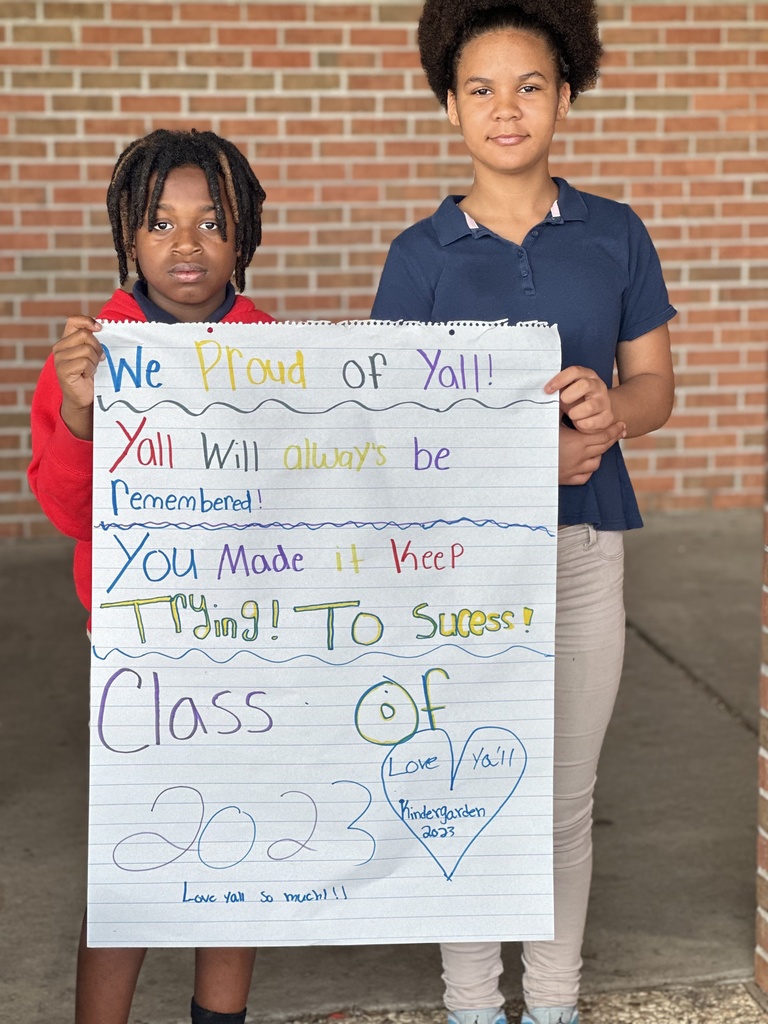 Two older children hold a banner with encouraging remarks for younger children.