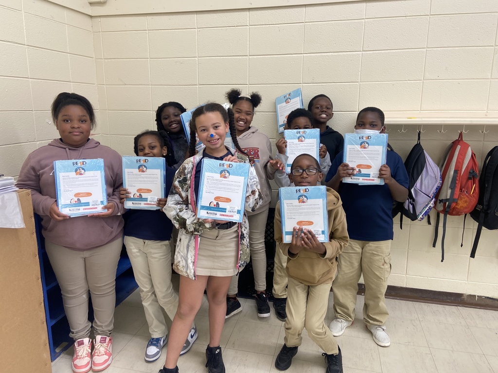 Smiling children holding up packets of books with a cover letter.